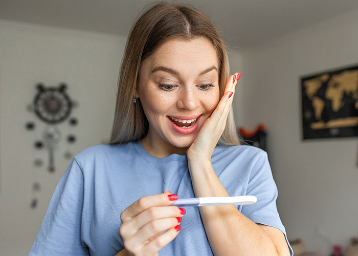 Young woman excitedly looking at a positive pregnancy test, illustrating psychic predictions that actually came true.