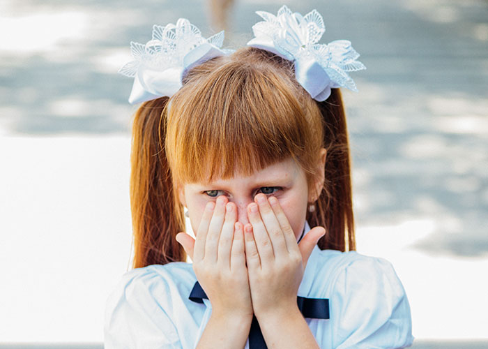 Young girl covering her face with hands, symbolizing surprise in stories where psychic predictions came true.