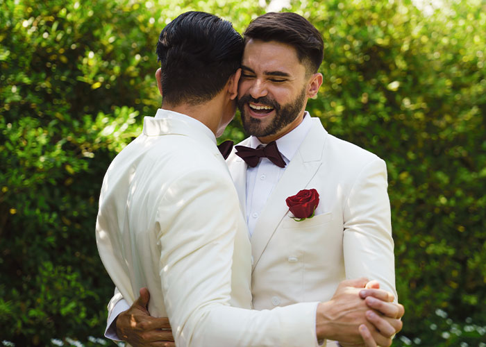 Two men in white suits smiling and embracing outdoors, illustrating moments people were told by a psychic and it came true