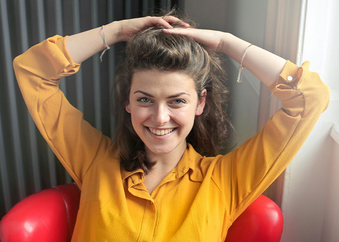 Young woman smiling confidently while sitting in a red chair, illustrating psychic predictions coming true moments.
