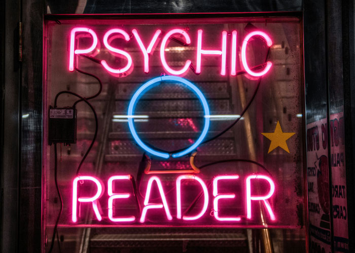 Neon psychic reader sign with a glowing crystal ball symbol, representing psychic predictions that actually came true.