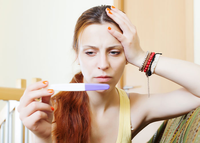 Young woman with worried expression holding a pregnancy test, illustrating psychic predictions that came true.