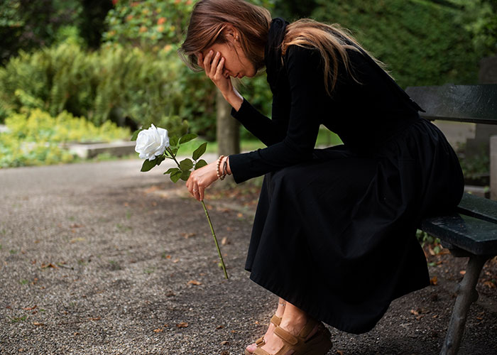 Woman in black dress sitting on a bench holding a white rose, reflecting on psychic predictions that came true.
