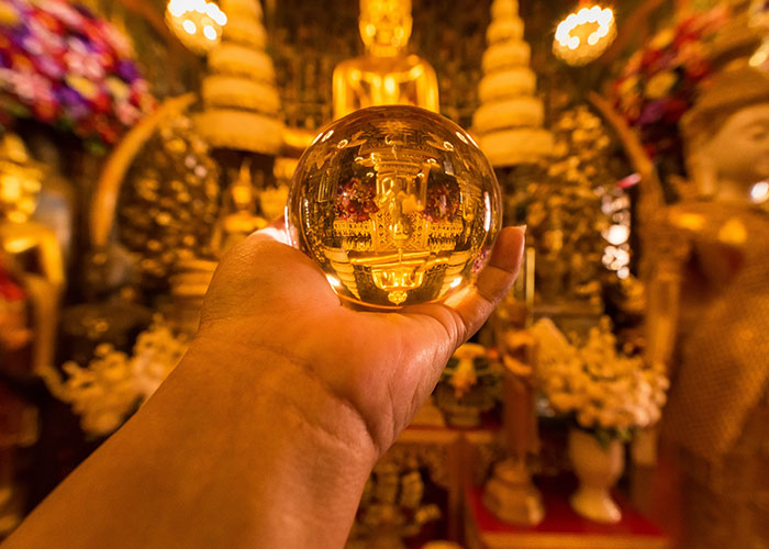 Hand holding a crystal ball reflecting a golden temple interior, symbolizing psychic predictions that came true.