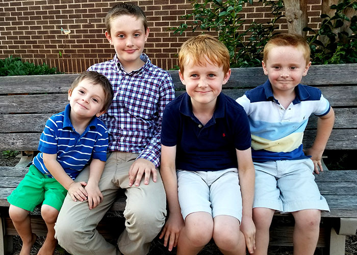 Four young boys sitting on a wooden bench outdoors, illustrating moments people were told something by a psychic that came true.