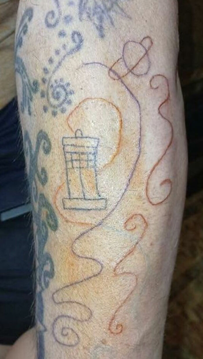Arm with unusual tattoos including an outline of a trash can and colorful swirly lines for tattoos.