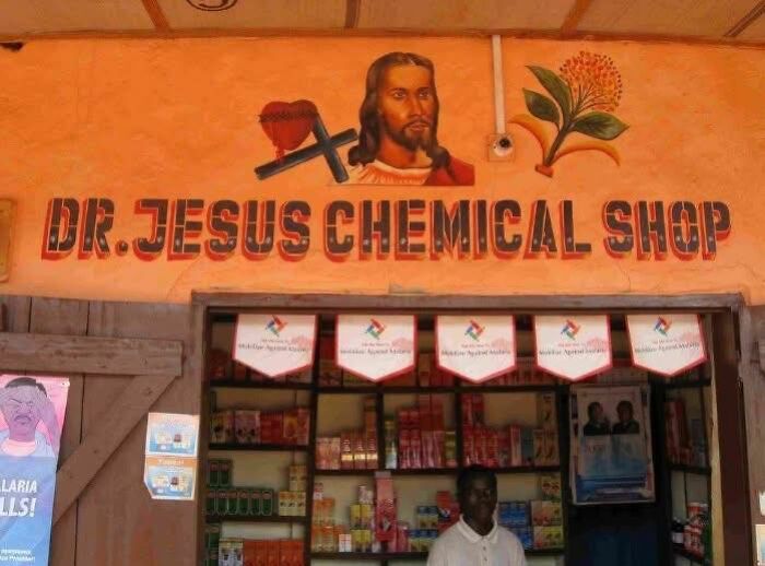 Exterior of Dr. Jesus Chemical Shop with a painted sign featuring religious imagery, showcasing an unusual out of context scene.