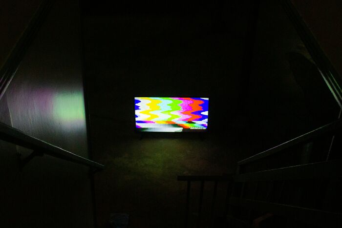 Dimly lit hospital stairway with a flickering colorful screen, setting an eerie scene for scary ghost stories at work.