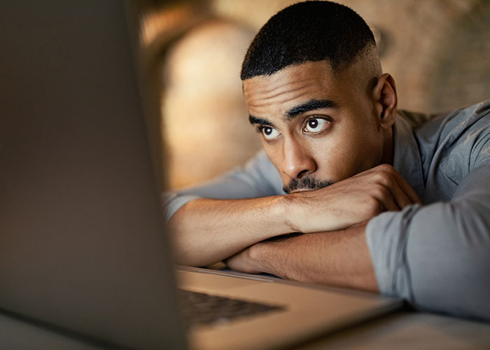Employee looking concerned and thoughtful while resting arms on desk, contemplating exposing management and HR issues.