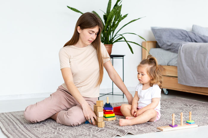 Babysitter looking shocked while playing with toddler, surprised by hidden disabled child, quitting and leaving immediately. Babysitter looking shocked while playing with toddler, surprised by hidden disabled child, quitting and leaving immediately.