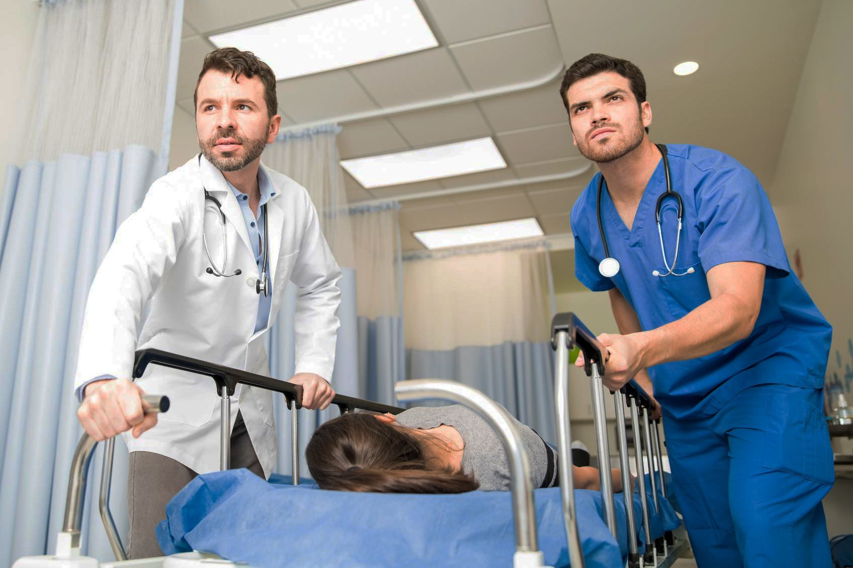 Two medical professionals pushing a hospital stretcher with a patient, highlighting refuse visiting girlfriend hospital concerns.