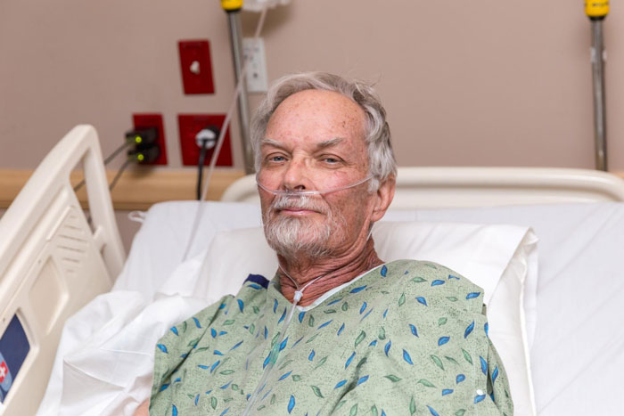 Elderly man in hospital bed with oxygen tube, representing refusing donate liver lawsuit patient scenario.