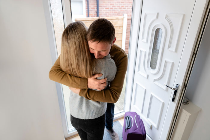 Woman spending $500 for Thanksgiving hugs family at home with suitcase at the front door after Airbnb-like experience