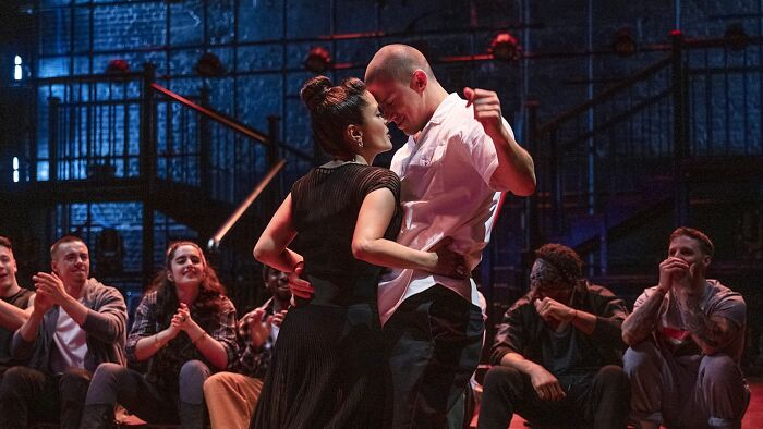 Couple dancing closely on stage with audience watching, capturing moments of drunk fumbles and hilarious fails.