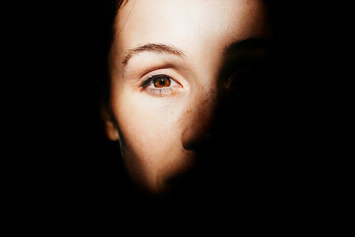 Close-up of a woman's face with light on one eye, illustrating themes of infinite luck or happiness choice scenarios.