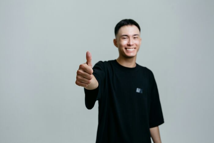 Young man smiling and giving thumbs up, representing infinite luck or happiness in a positive scenario choice.