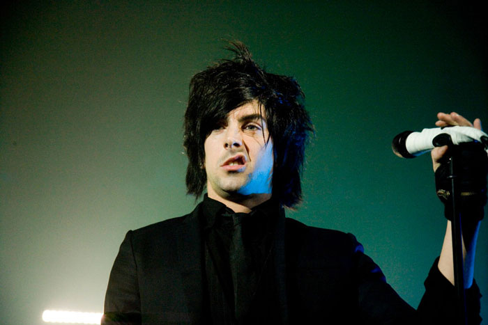 Rock star performing on stage with microphone, known for serving prison time for crimes against children.