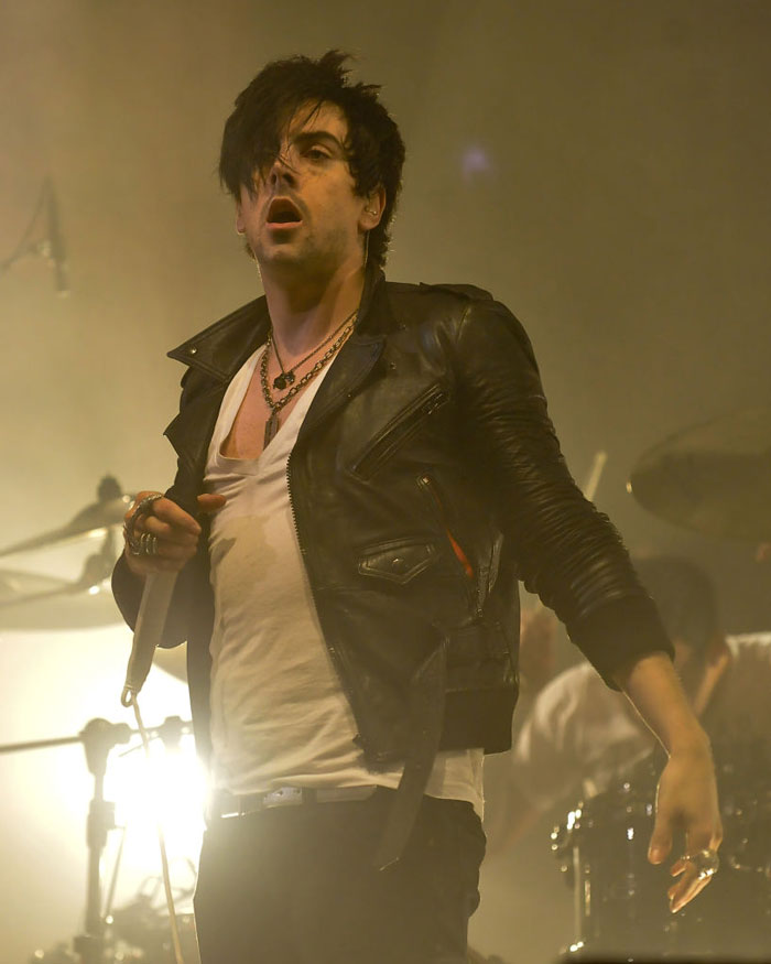 Rock star performing on stage in leather jacket, spotlight shining, related to fatal prison attack news.