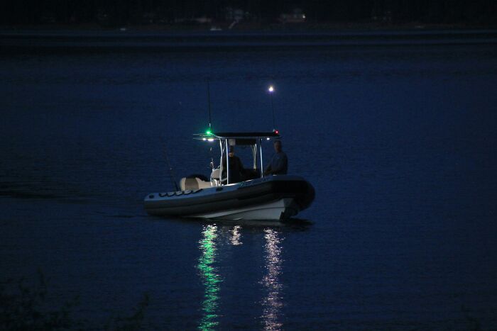 Two people on a small boat at night with navigation lights, illustrating moments the universe protected from harm.