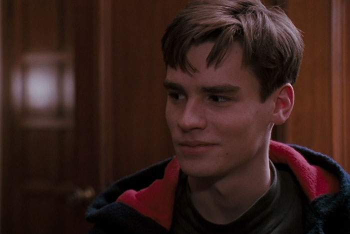 Young man with brown hair wearing a dark jacket with red lining, captured in a heartfelt moment from movies tugging at heartstrings.