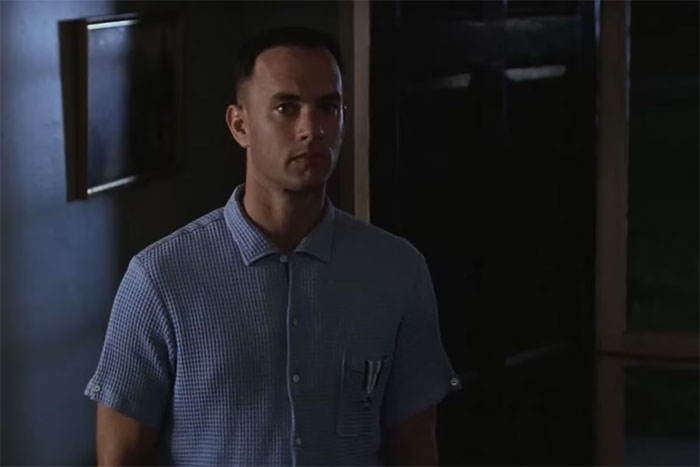 Man in a blue shirt standing in a dimly lit room, representing iconic lines from movies that tug at the heartstrings.