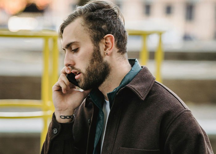 Young man in a coat talking seriously on phone, reporting sister to CPS about her illegal adoption plan. Young man in a coat talking seriously on phone, reporting sister to CPS about her illegal adoption plan.