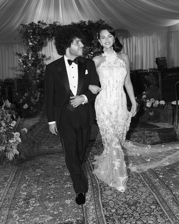 Selena Gomez and her kidney donor walking arm in arm at a wedding with floral decorations and elegant attire. Selena Gomez and her kidney donor walking arm in arm at a wedding with floral decorations and elegant attire.