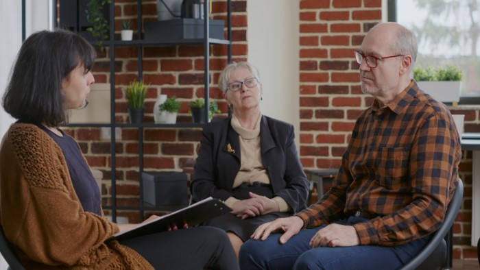 Man and woman in a therapy session discussing a doctor refusing to rehire sister after costing the practice money