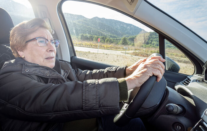 Elderly woman driving a car focused on the road, illustrating independence and smart use of loopholes.