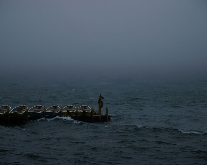 Small boats docked on a foggy ocean with dark waves, evoking weird and fascinating things that happened in the ocean.