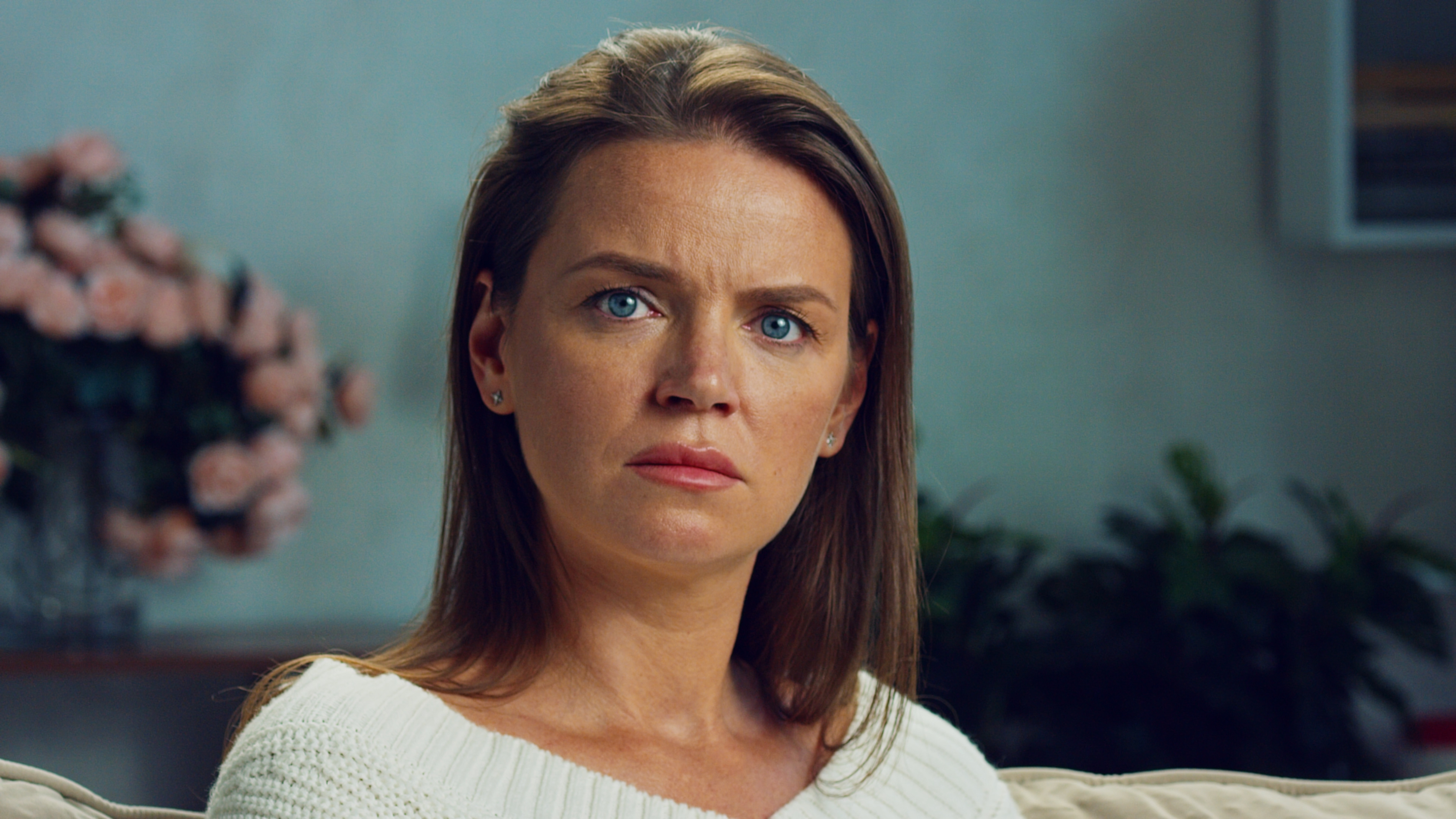 Woman throwing a tantrum looking upset in a living room, upset about stepson's inheritance from late mother.