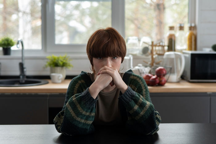 Teenager looking frustrated in kitchen after parents gift 17YO golden child $25K car while older sibling gets phone case