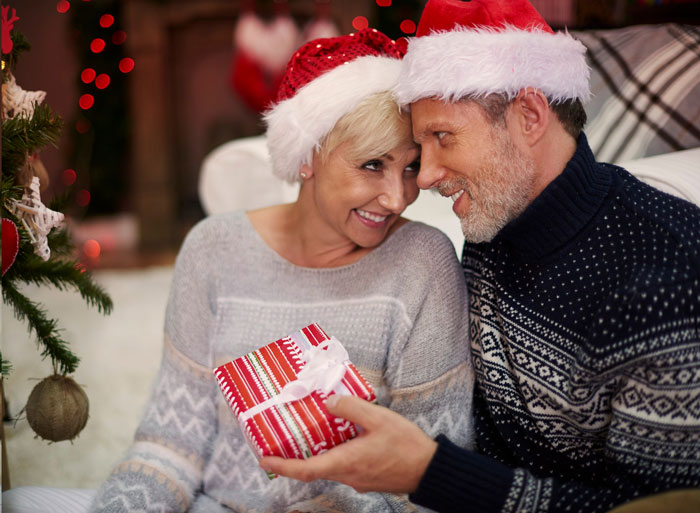 Couple wearing Santa hats exchanging Christmas gifts, symbolizing parents gift dynamics and golden child car gift story.