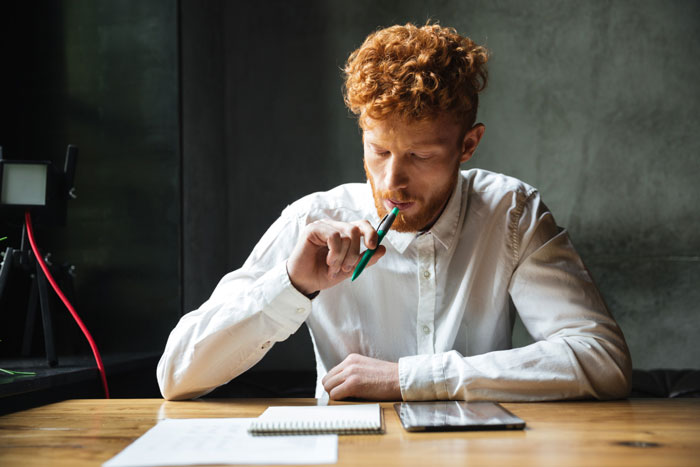 Man in a white shirt writing a book, thinking deeply, related to guy thinks he married the wrong sister story.
