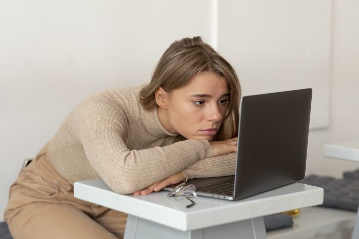 Young woman looking worried while working on laptop, illustrating boss wife claim affecting an innocent worker.