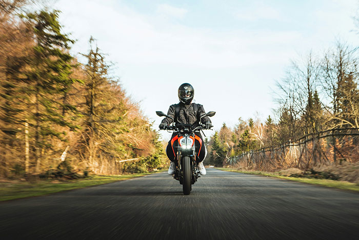 Person riding a motorcycle on a forest road, illustrating unexpected hospital visits leading to surgery cases.