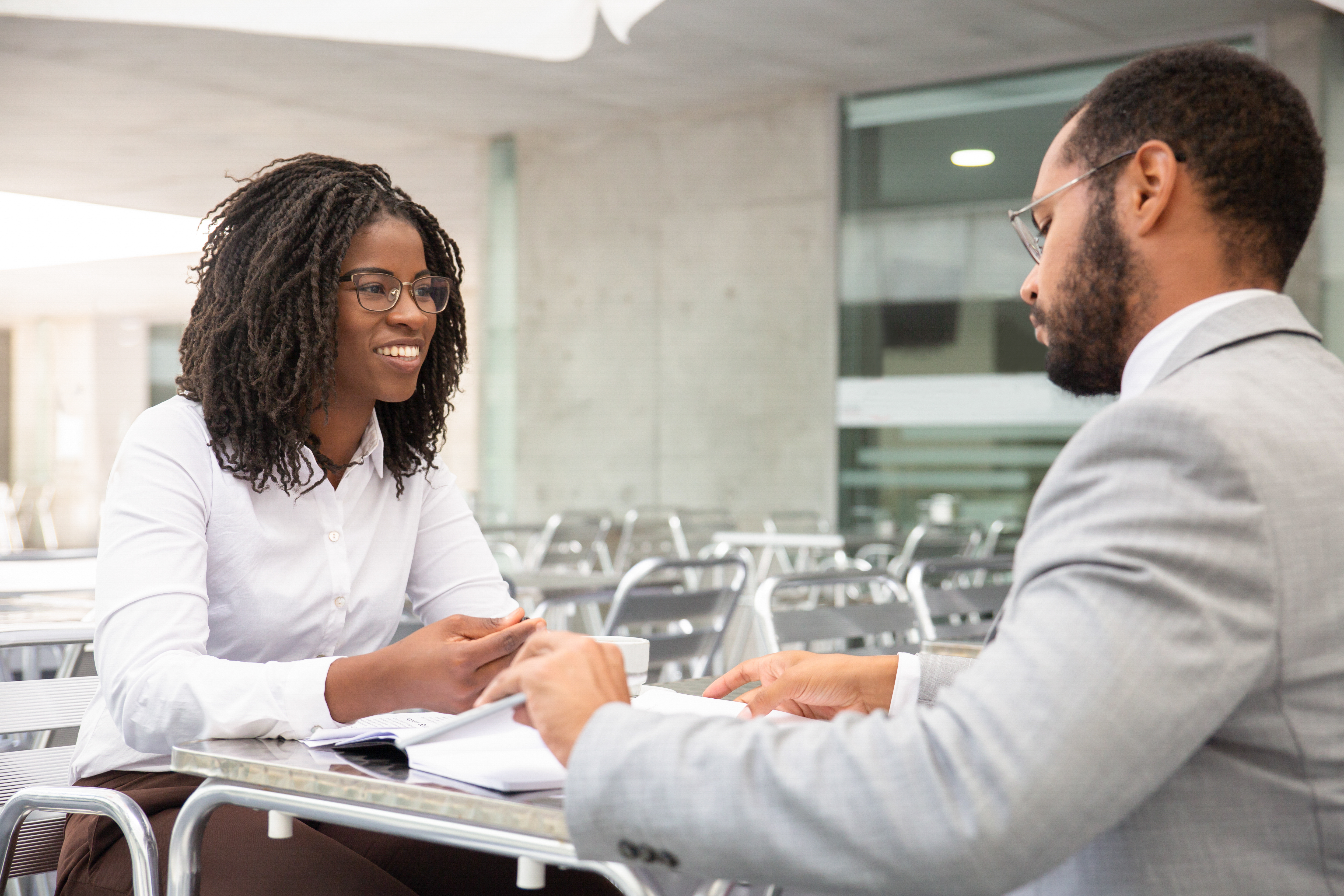 Professional woman in a white shirt interviewing with a man in a gray suit, highlighting job offers after name change.