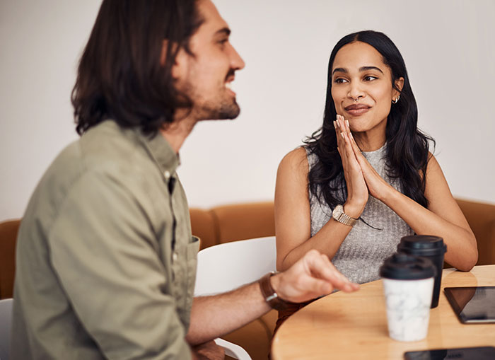 Two people having a conversation at a table, showing body language and social cues that can be confusing to interpret.