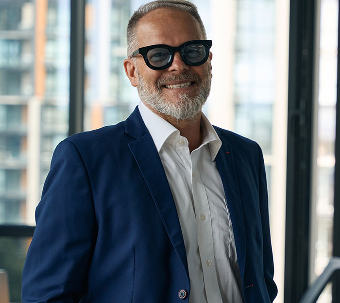Smiling man in glasses and blue blazer representing people sharing social cues that confuse them.