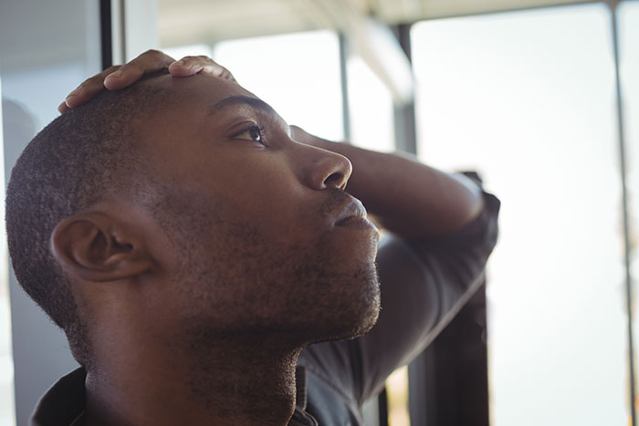 Young man looking thoughtful and confused, struggling with social cues in a bright indoor setting.