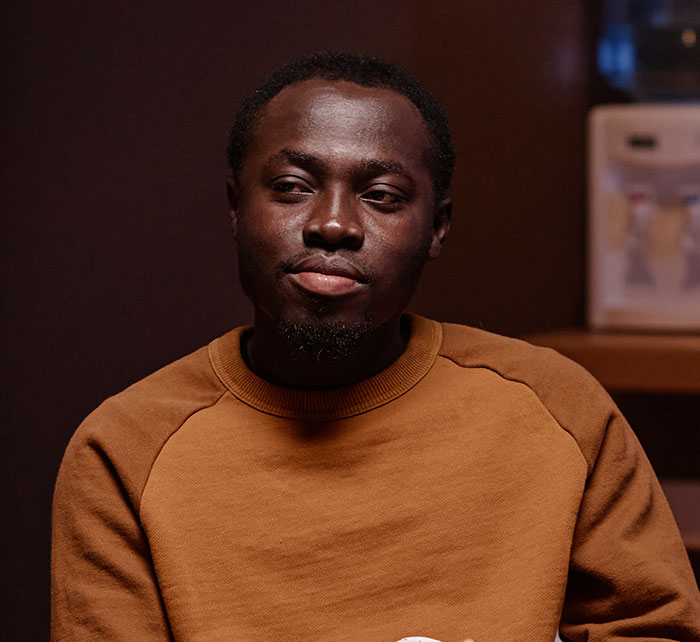 Young man in brown sweater looking thoughtful, illustrating social cues that confuse people in everyday interactions.