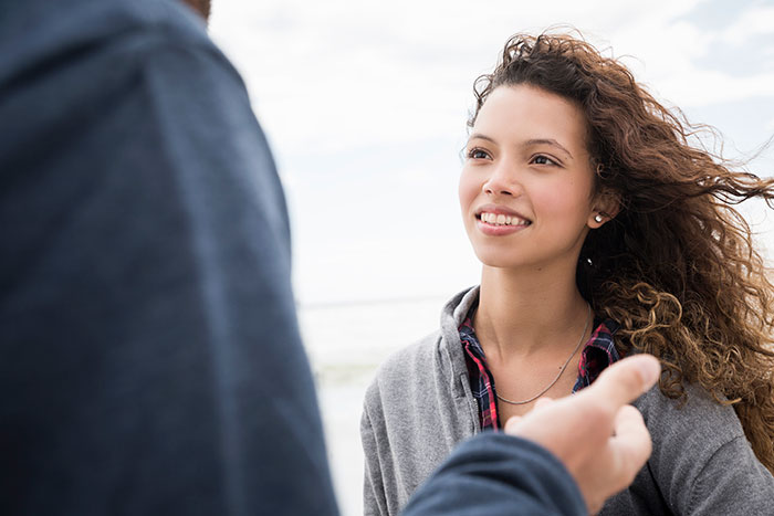 Young woman with curly hair listening attentively in a conversation, illustrating social cues that confuse people.