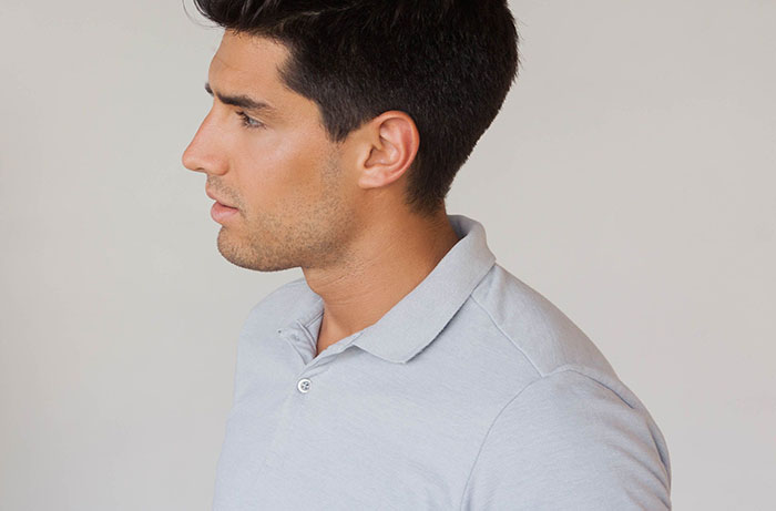 Young man in a light gray polo shirt looking sideways, illustrating social cues that confuse people in conversations.