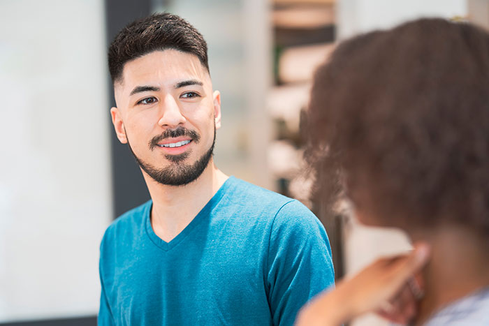 Young man in blue shirt looking confused during a conversation illustrating social cues that confuse people.