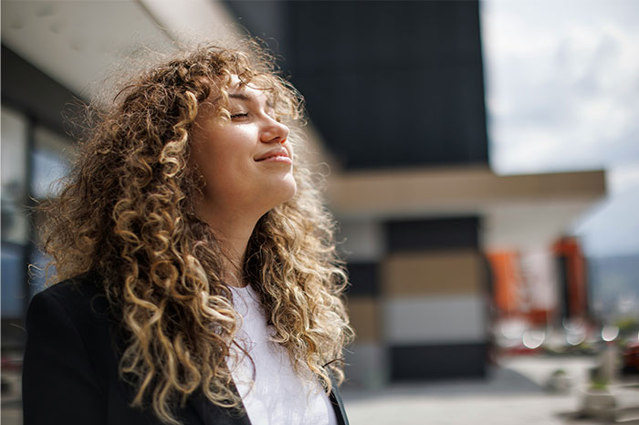 Young woman with curly hair enjoying a moment, illustrating high social skills in conversations and communication.