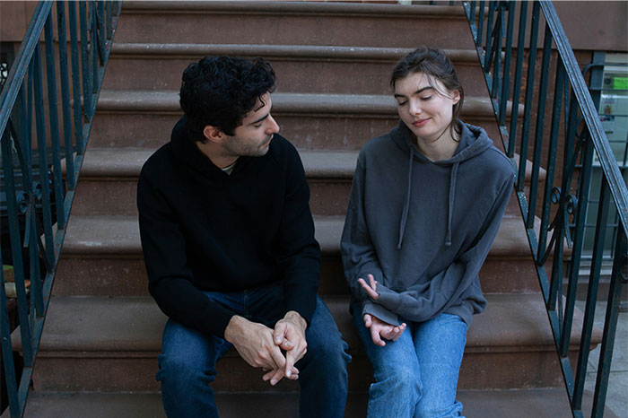 Two people with high social skills sitting on stairs engaged in a thoughtful conversation about common mistakes.
