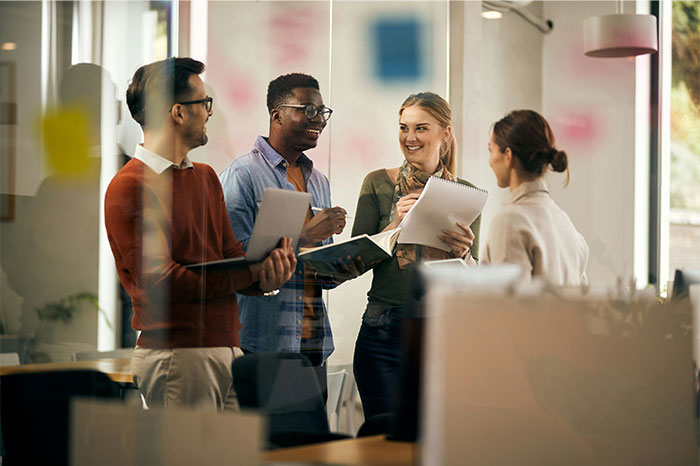 A diverse group with high social skills sharing ideas and notes during a friendly conversation in an office setting.
