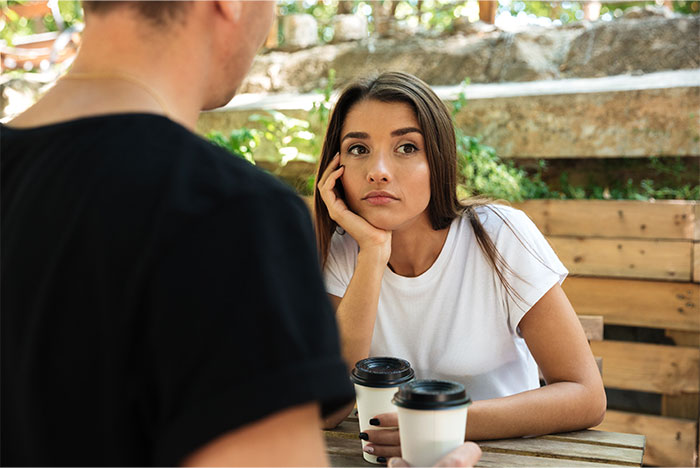 Two people having a conversation at a cafe, illustrating common mistakes in social skills during discussions.