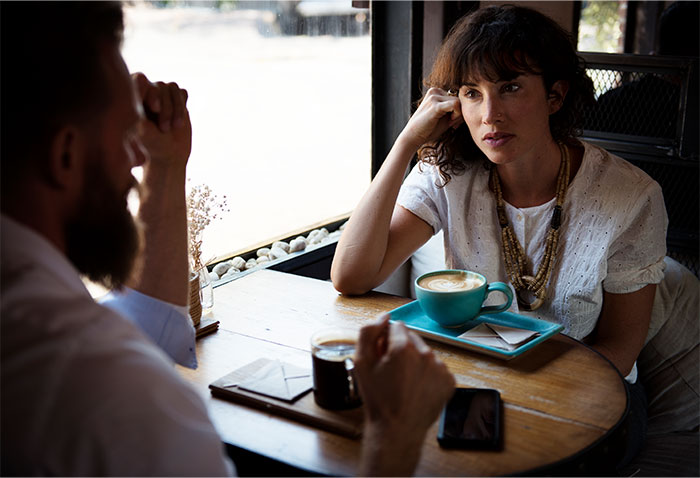 Two people with high social skills engaged in a deep conversation at a café table with coffee cups.