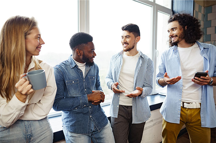 Four diverse friends with high social skills engaged in a lively conversation near a bright window.